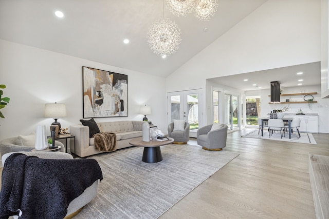 living room featuring a notable chandelier, french doors, high vaulted ceiling, and light wood-type flooring