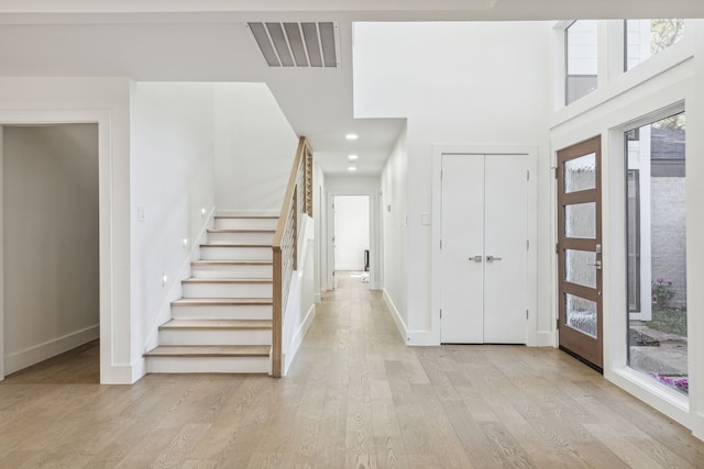 entryway featuring a towering ceiling and light wood-type flooring