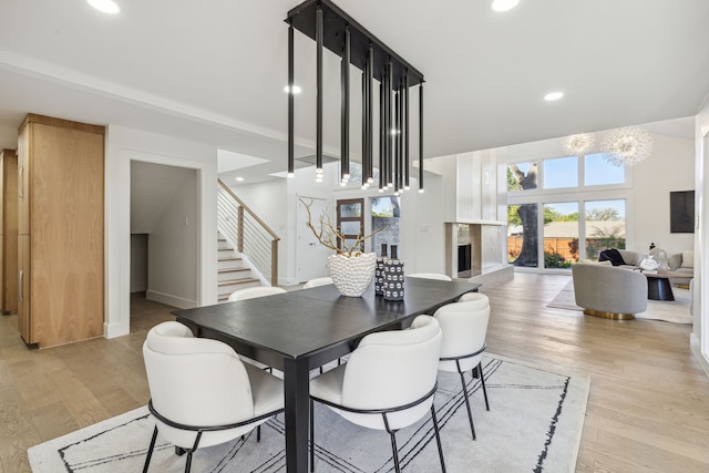 dining room with light hardwood / wood-style floors, a premium fireplace, and a chandelier