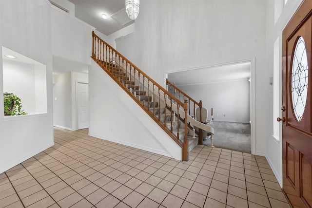 foyer entrance with light tile patterned flooring and a towering ceiling