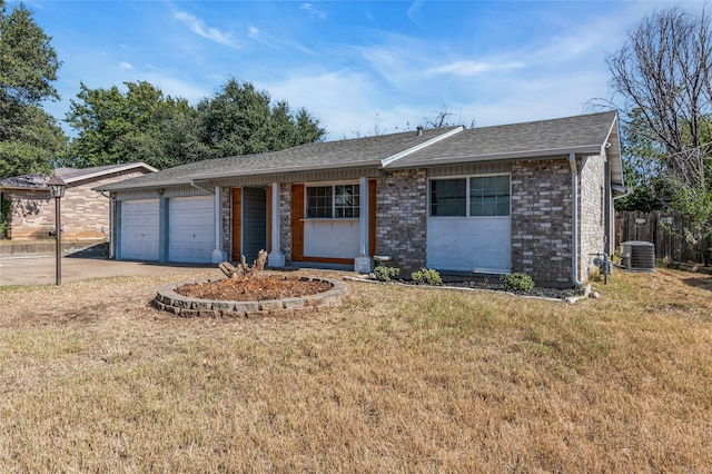 ranch-style house featuring a garage, cooling unit, and a front yard