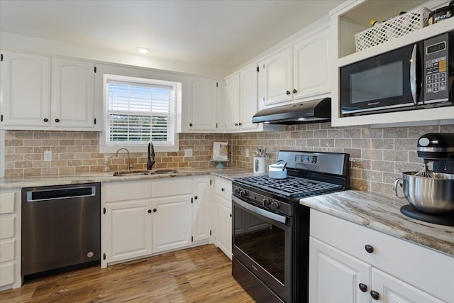 kitchen with sink, black appliances, light hardwood / wood-style flooring, and white cabinets