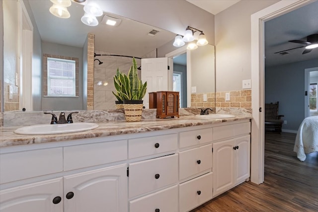 ensuite bathroom featuring a sink, visible vents, connected bathroom, and wood finished floors