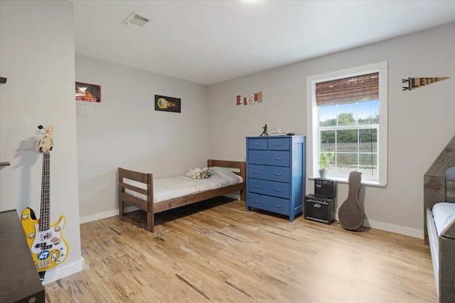 bedroom with baseboards, visible vents, and light wood-type flooring