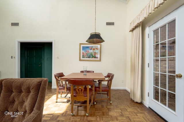 dining space with a towering ceiling and parquet floors