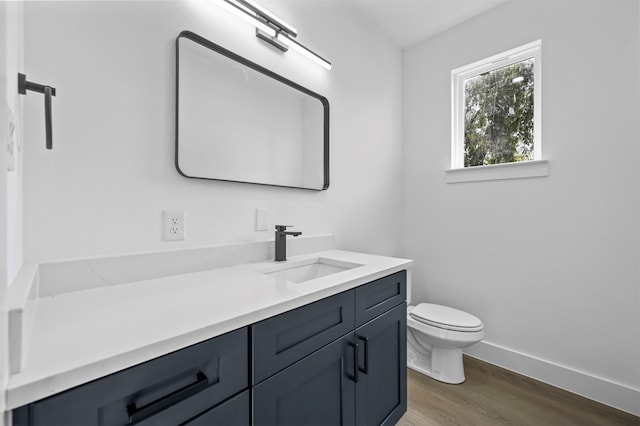 bathroom with toilet, hardwood / wood-style floors, and vanity