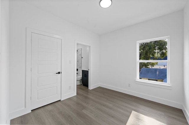 unfurnished bedroom featuring ensuite bath and light hardwood / wood-style floors