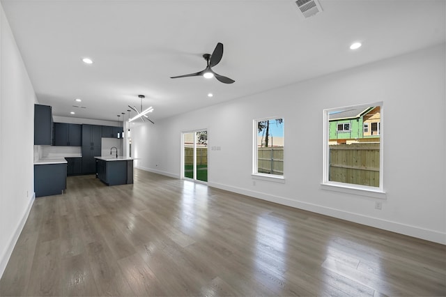 unfurnished living room with ceiling fan, sink, and dark hardwood / wood-style floors