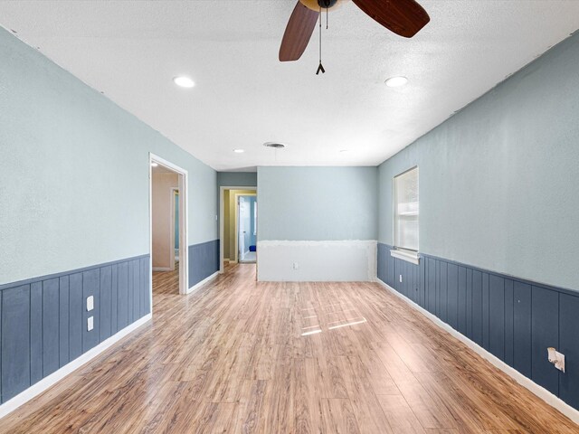 spare room featuring ceiling fan, light hardwood / wood-style flooring, and a textured ceiling