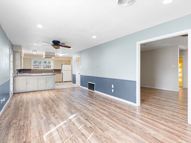 unfurnished living room featuring ceiling fan, sink, and light hardwood / wood-style floors