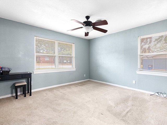 carpeted spare room featuring a wealth of natural light and ceiling fan