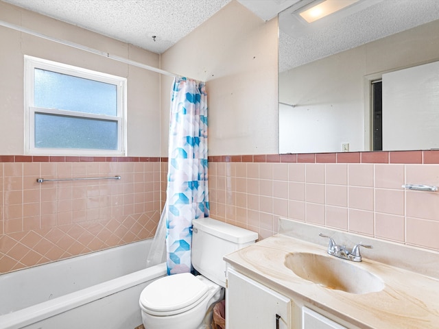 full bathroom featuring shower / tub combo with curtain, toilet, a textured ceiling, tile walls, and vanity