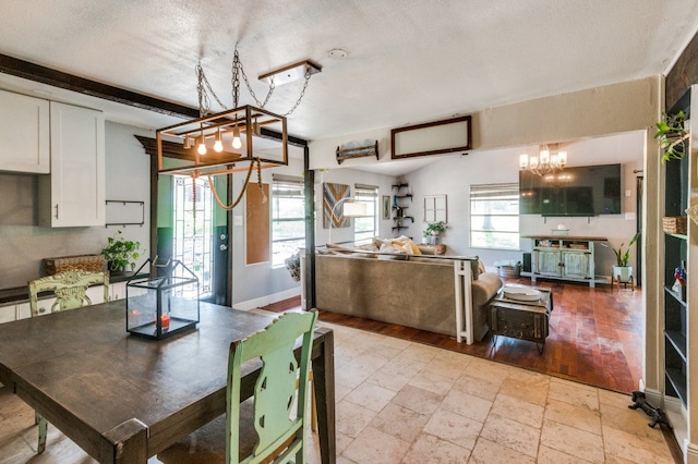 dining space with a textured ceiling, light hardwood / wood-style floors, and an inviting chandelier