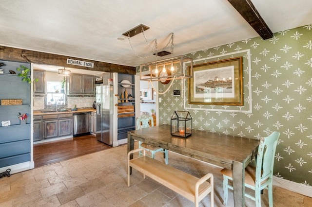 dining room with beamed ceiling, light hardwood / wood-style floors, and sink