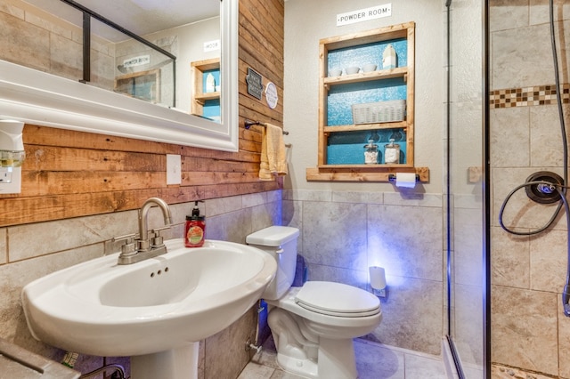 bathroom with toilet, a shower with shower door, and tile walls