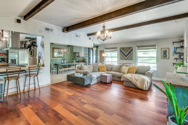 living room featuring vaulted ceiling with beams, a chandelier, and hardwood / wood-style flooring