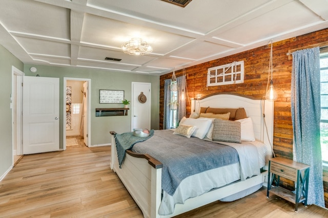 bedroom featuring hardwood / wood-style floors, coffered ceiling, wooden walls, and ensuite bath