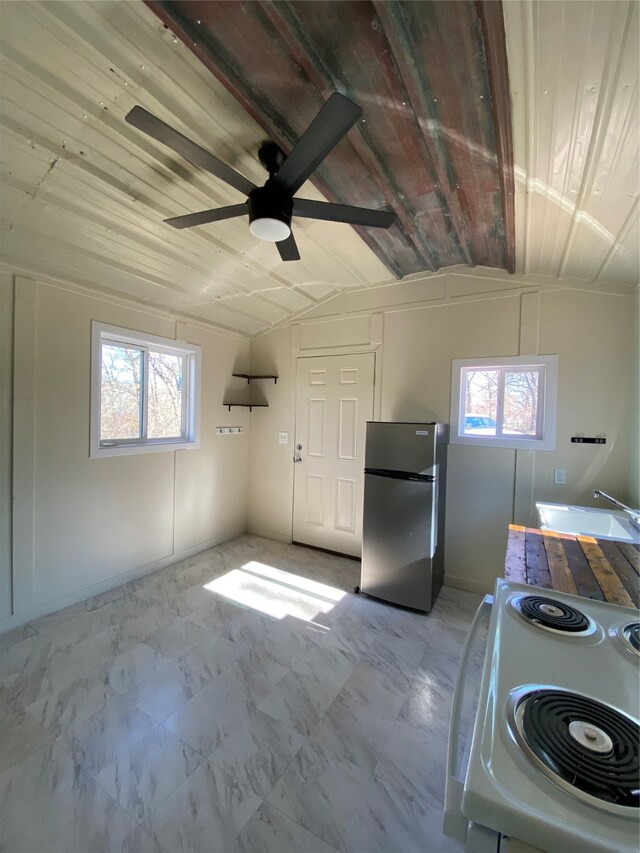 kitchen featuring lofted ceiling, sink, electric range, a healthy amount of sunlight, and stainless steel refrigerator