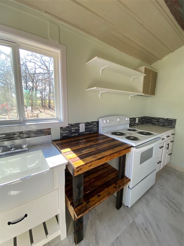 kitchen with electric stove and white cabinetry