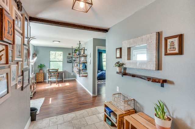 hall with beam ceiling, a textured ceiling, and light hardwood / wood-style floors