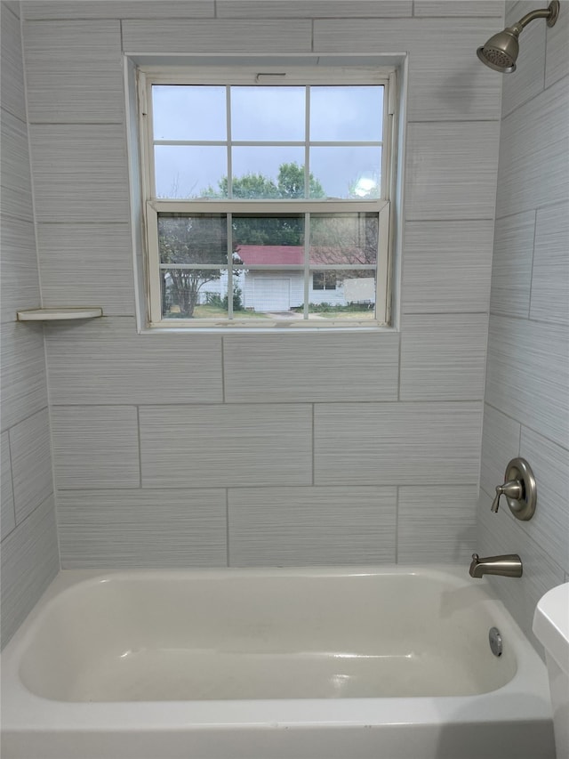 bathroom featuring tiled shower / bath combo and toilet