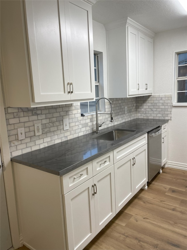 kitchen featuring stainless steel dishwasher, white cabinets, and sink