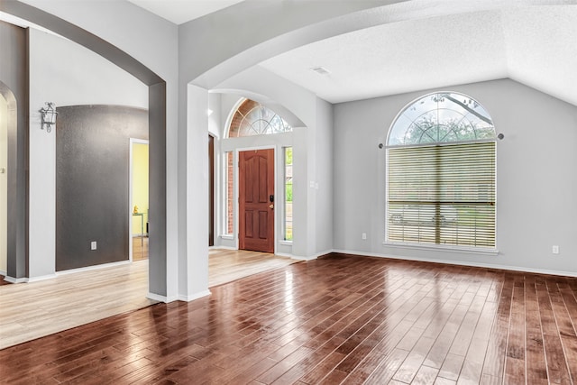 entrance foyer featuring hardwood / wood-style flooring, a textured ceiling, and vaulted ceiling