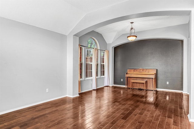 unfurnished living room with vaulted ceiling and dark hardwood / wood-style flooring