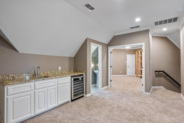 interior space featuring light carpet, sink, vaulted ceiling, beverage cooler, and white cabinetry