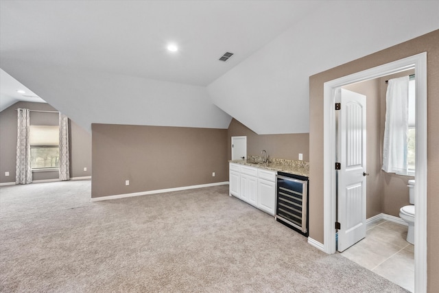 bar featuring lofted ceiling, white cabinets, light colored carpet, and beverage cooler