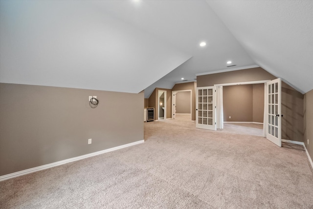 additional living space featuring light carpet, lofted ceiling, and french doors