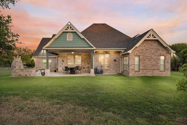 back house at dusk featuring a yard, a patio area, and area for grilling