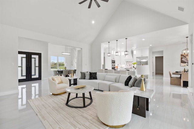 tiled living room with high vaulted ceiling and ceiling fan with notable chandelier