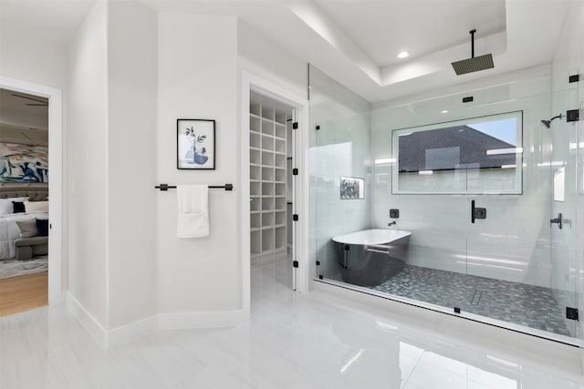 full bathroom featuring a stall shower, baseboards, a tray ceiling, a freestanding tub, and recessed lighting