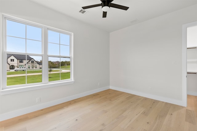 unfurnished room with a ceiling fan, light wood-type flooring, visible vents, and baseboards