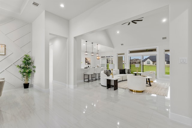 living room with ceiling fan, marble finish floor, a high ceiling, and visible vents