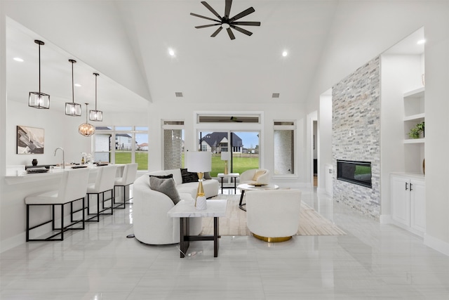 living room with built in shelves, a fireplace, high vaulted ceiling, and a ceiling fan