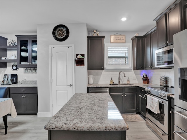 kitchen featuring tasteful backsplash, appliances with stainless steel finishes, sink, a center island, and light hardwood / wood-style flooring