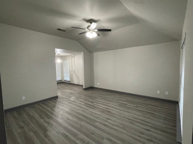 interior space with ceiling fan with notable chandelier, vaulted ceiling, and dark hardwood / wood-style flooring