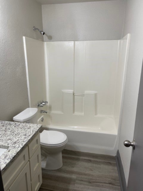 full bathroom with vanity, toilet, hardwood / wood-style flooring, and washtub / shower combination