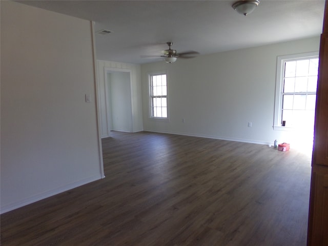 empty room with dark hardwood / wood-style flooring, ceiling fan, and plenty of natural light