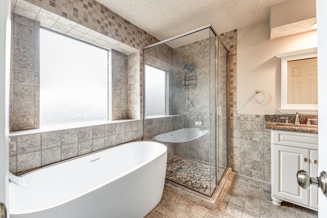 bathroom featuring tile walls, vanity, independent shower and bath, and a textured ceiling