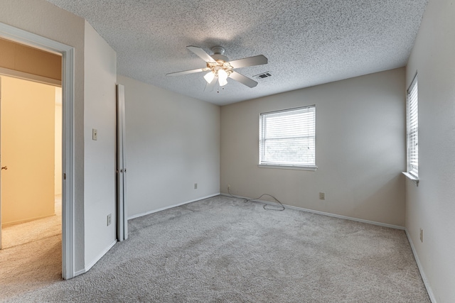 spare room with ceiling fan, light carpet, and a textured ceiling