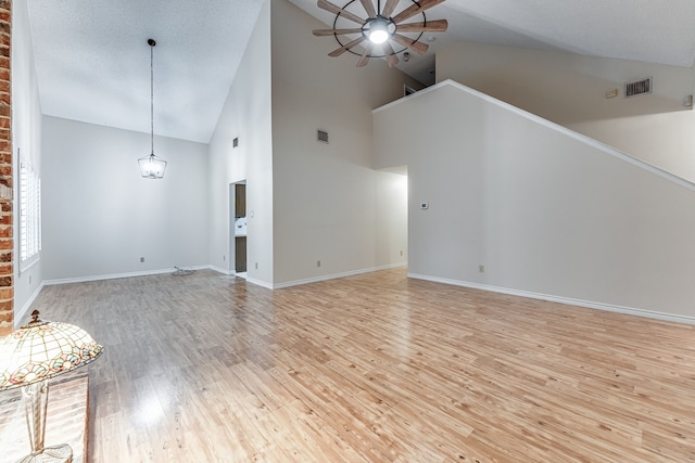 unfurnished living room featuring light hardwood / wood-style flooring, a textured ceiling, high vaulted ceiling, and ceiling fan