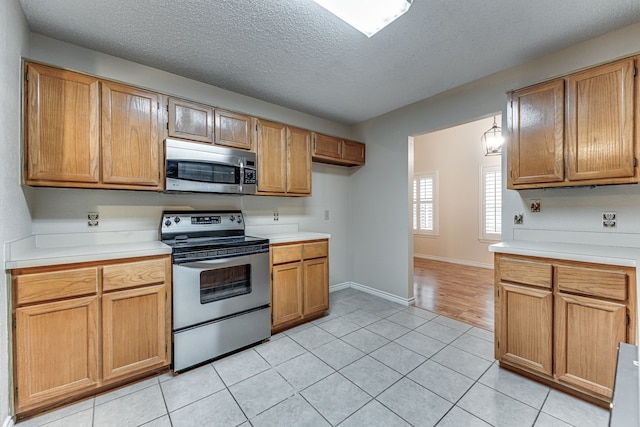 kitchen featuring stainless steel appliances, a textured ceiling, and light tile patterned floors