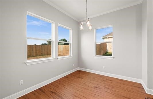 unfurnished room featuring crown molding, wood-type flooring, and a chandelier