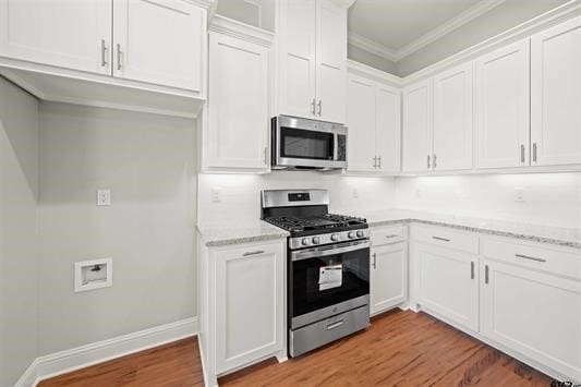 kitchen featuring crown molding, stainless steel appliances, light stone countertops, and white cabinets