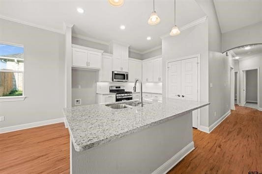 kitchen featuring appliances with stainless steel finishes, sink, light wood-type flooring, an island with sink, and white cabinetry