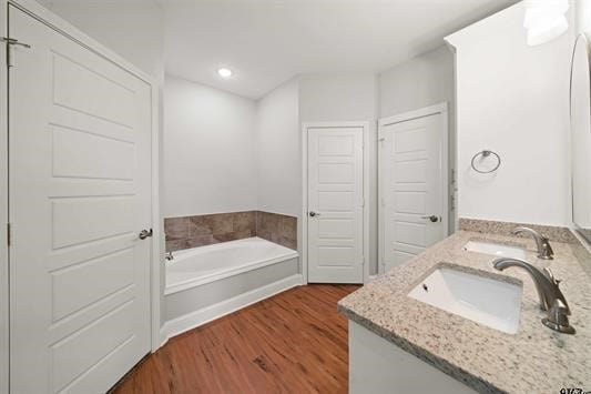 bathroom featuring vanity, wood-type flooring, and a bath