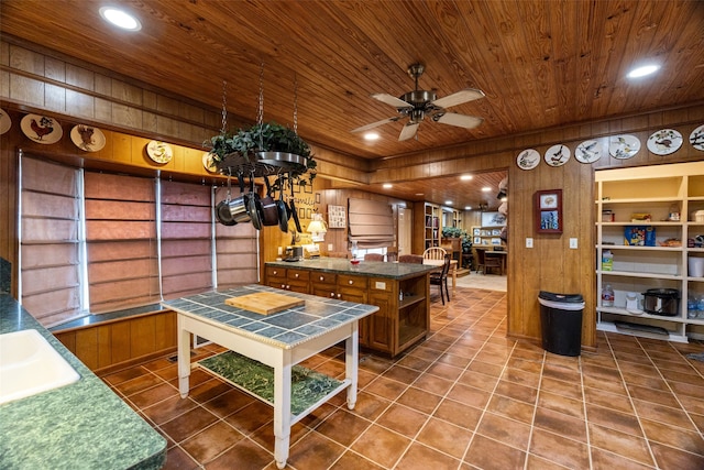 kitchen featuring a kitchen island, wood ceiling, ceiling fan, tile patterned floors, and wooden walls